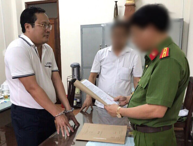 Phan Huy Khang listens to his arrest warrant in this photo provided by the police.
