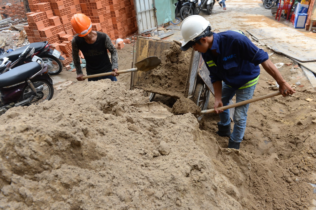 Two workers pass sand through a sieve at a construction site in Ho Chi Minh CIty. Photo: Tuoi Tre