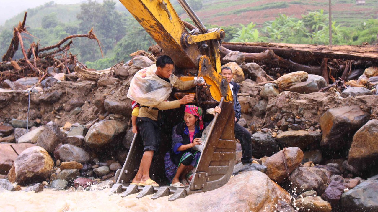The family of local resident Vang A Tua is taken across the Nam Pam Stream in Son La Province in an excavator bucket, August 16, 2017. Photo: Tuoi Tre