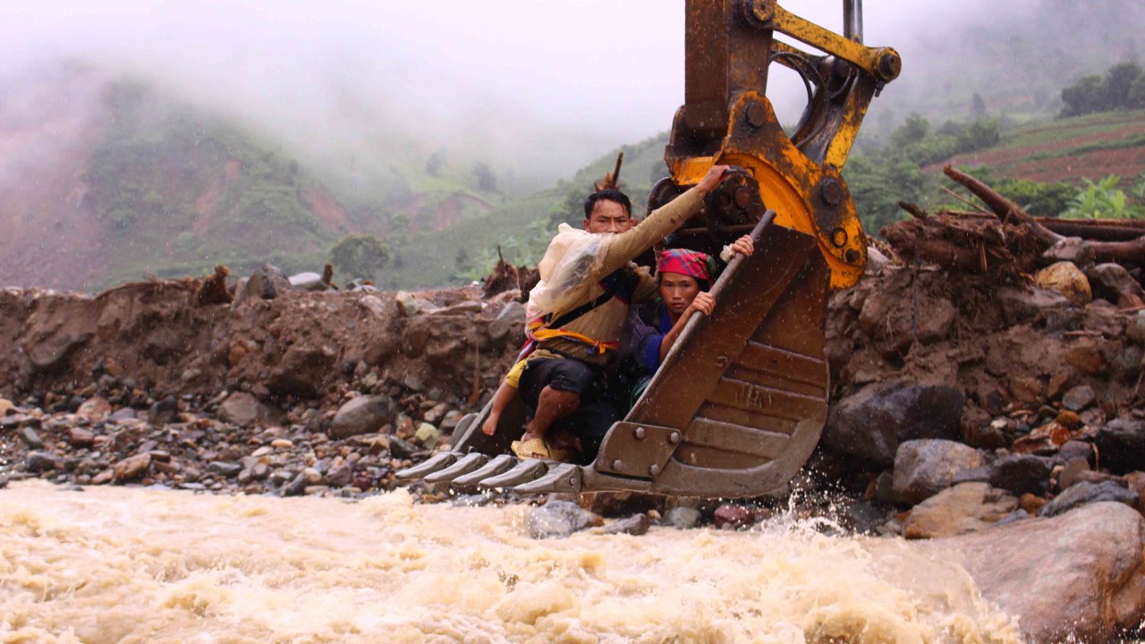 The family of local resident Vang A Tua is taken across the Nam Pam Stream in Muong La District, Son La Province in an excavator bucket, August 16, 2017. Photo: Tuoi Tre