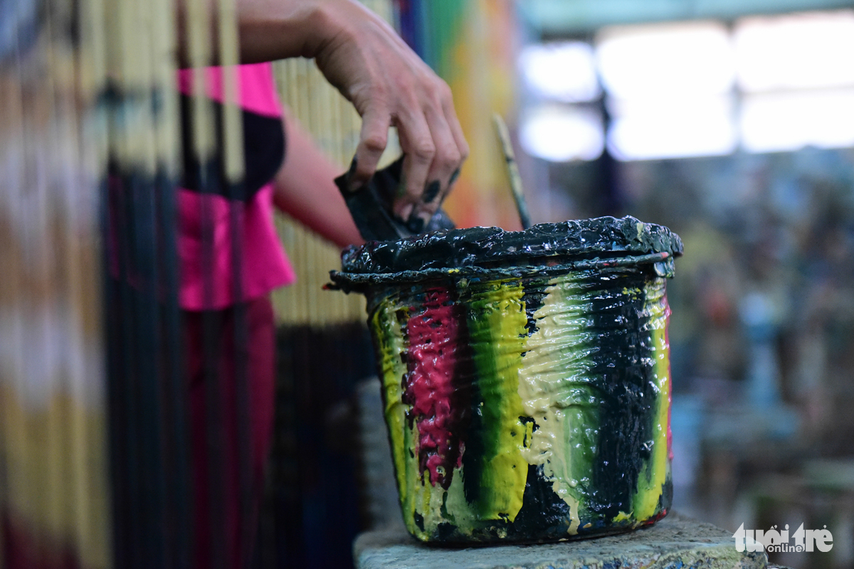The job of hand-painting bamboo curtain can be dirty and strenuous. Photo: Tuoi Tre