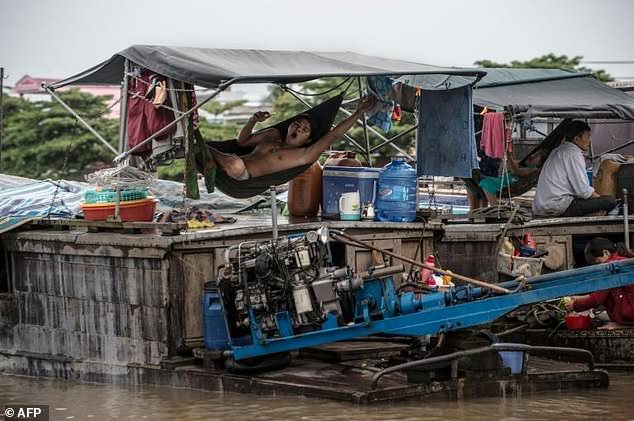 A resident of a house boat yawns as he swings on a hammock on the vessel in a canal off the Hau River at the floating Cai Rang Market in Can Tho, a small city in the Mekong Delta. Photo: AFP