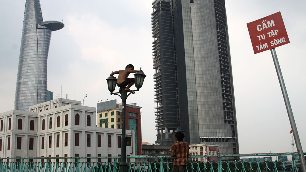 A child climbs onto a lamp post on the Mong Bridge. Photo: Tuoi Tre