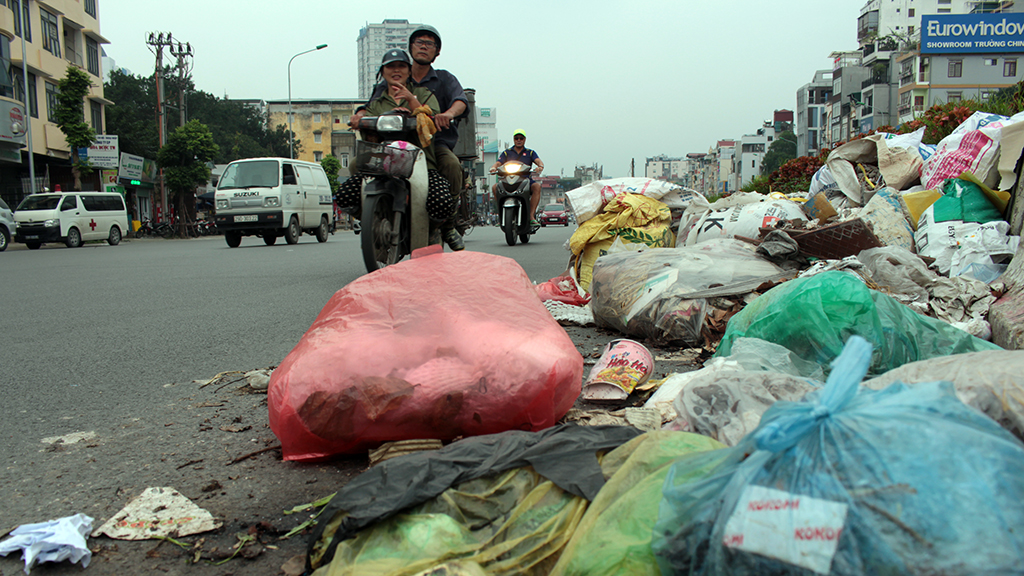 Countless bags of trash fills the sidewalk and roadway on Truong Chinh Street.
