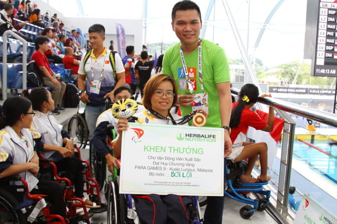 Vietnam’s disabled swimmer Vi Thi Hang poses with a symbolic cash bonus granted by Herbalife. Photo: Tuoi Tre