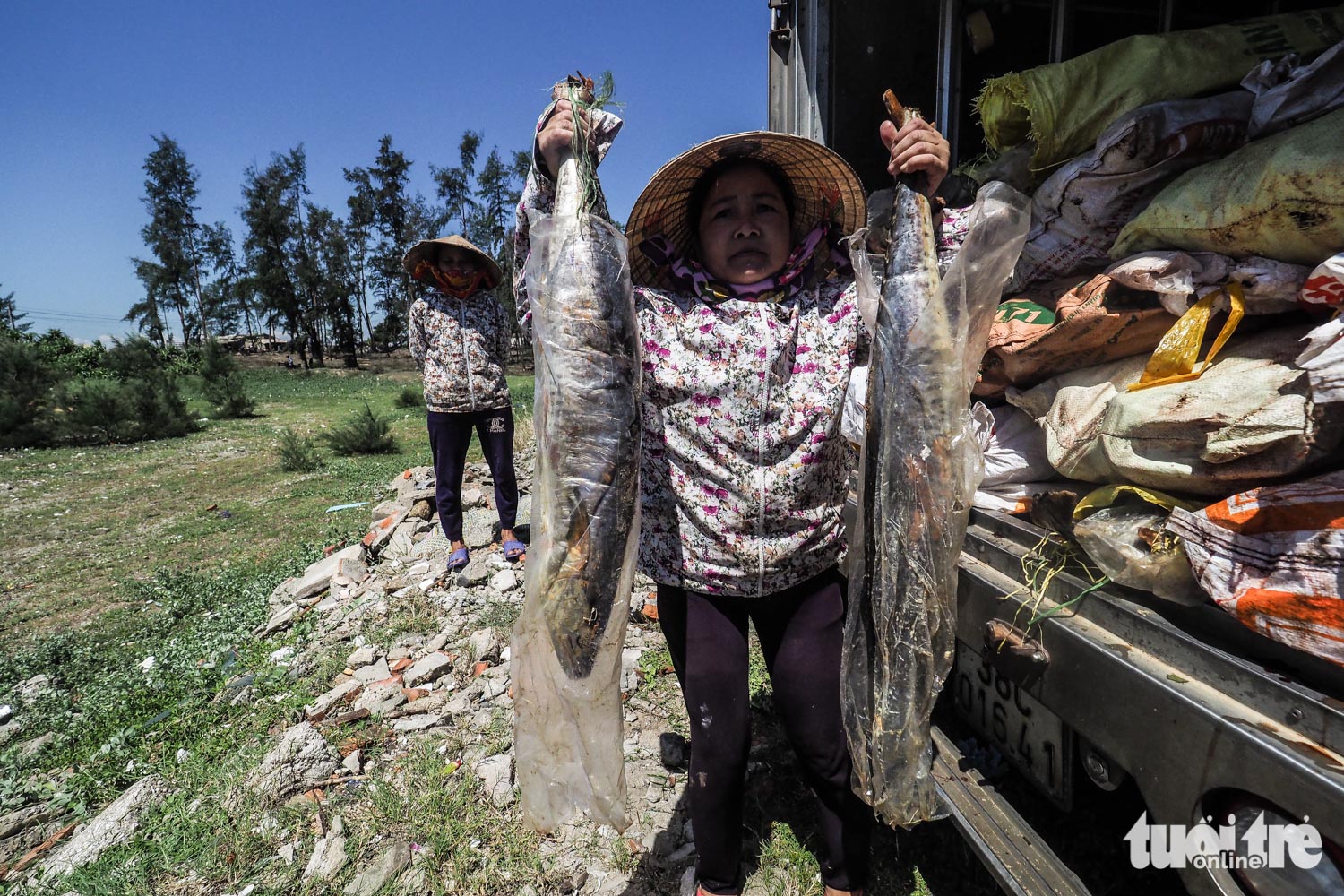 A resident displays two fish that await disposal.
