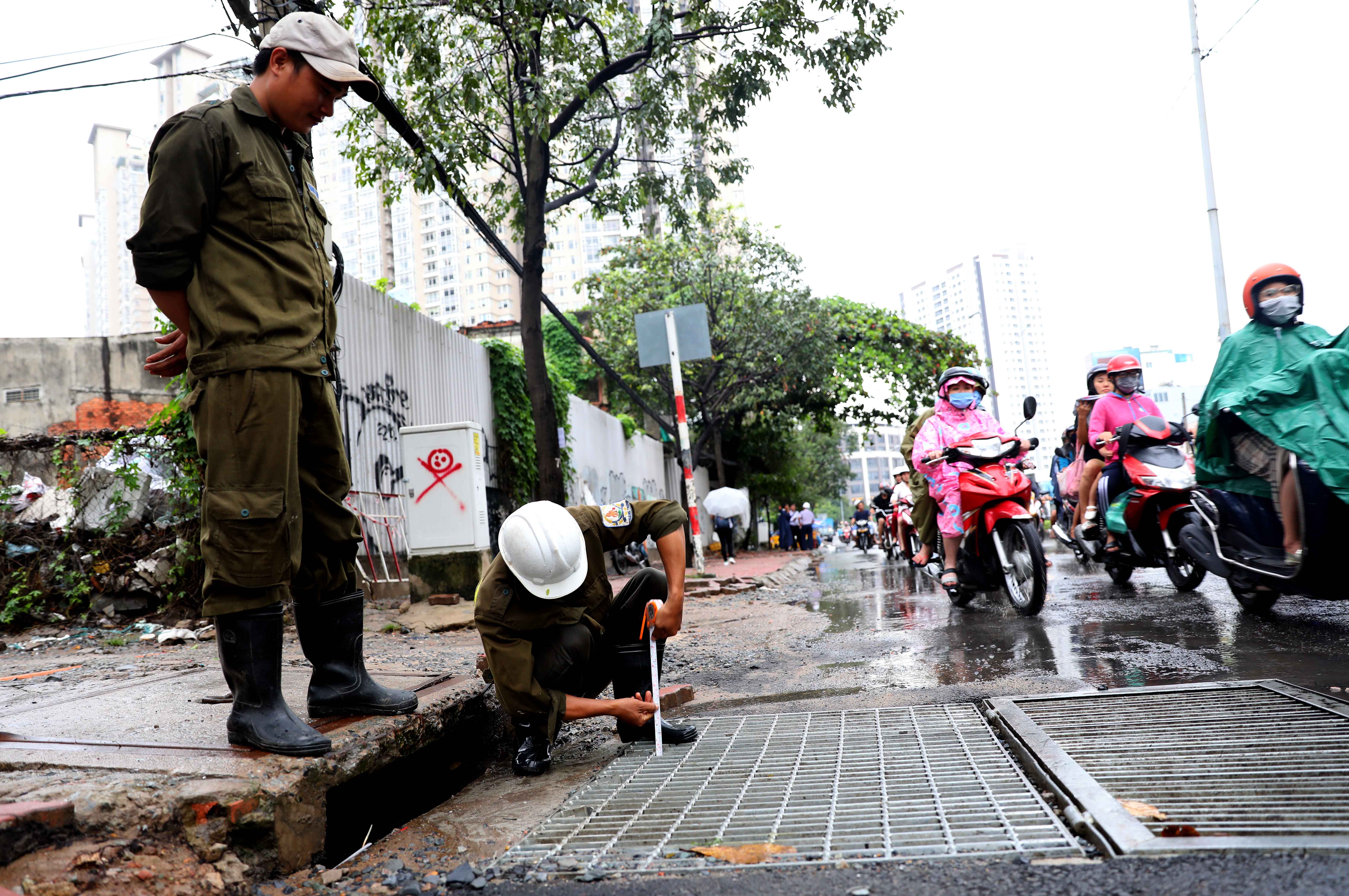 A man measure the water level on Nguyen Huu Canh Street following the use of the pump system.