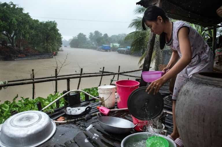 Sixteen-year-old Dang Thi Bich Thien washes the dishes during a morning monsoon downpour at her home in Thuan Hung Village in Vietnam's Mekong Delta. Photo: AFP
