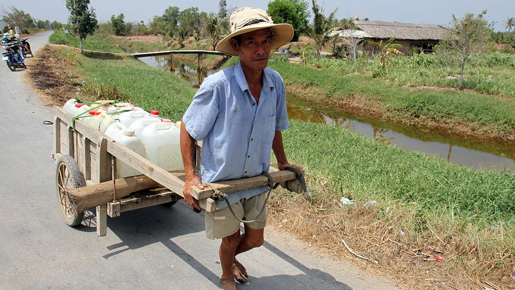 A resident carries bottles of groundwater for daily use as local rivers and canals have become polluted.