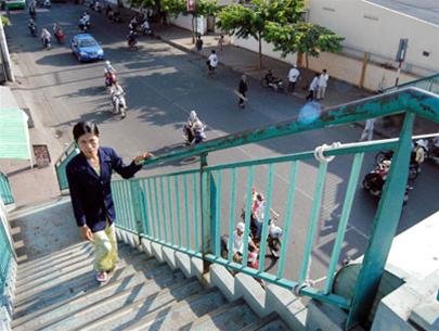 A woman walks up the stairs of a footbridge in front of the Oncology Hospital in Binh Thanh District. Photo: Tuoi Tre
