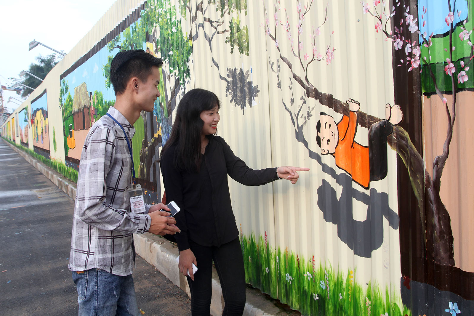 Two youths in Hanoi smile at a lovely illustration of a Vietnamese folk story. Photo: Tuoi Tre