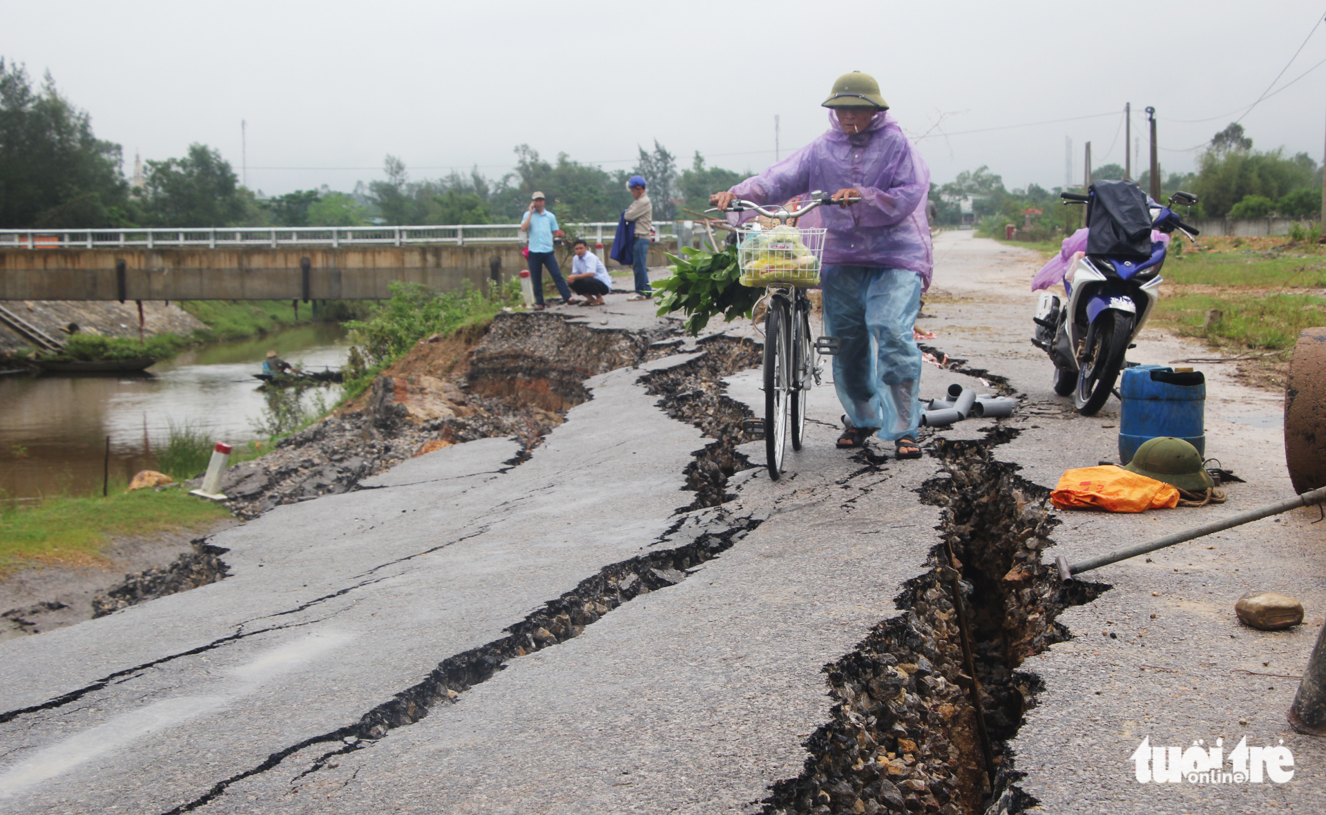 A resident pushes his bicycle between large cracks of the road. Photo: Tuoi Tre