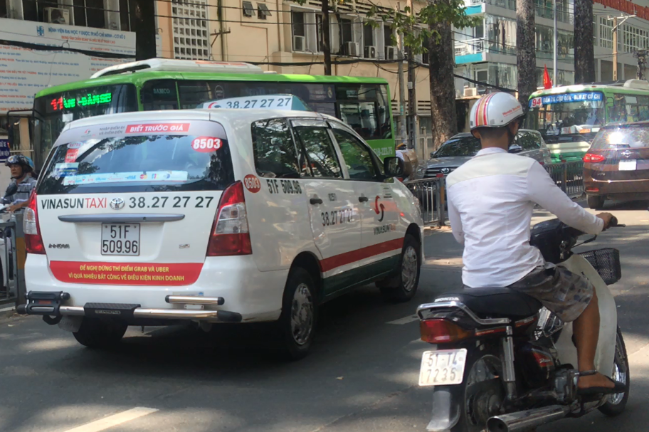 A Vinasun taxi with a bumper sticker carrying the message ‘the pilot schemes of Grab and Uber must end due to unfair business conditions’ in Ho Chi Minh City. Photo: Tuoi Tre