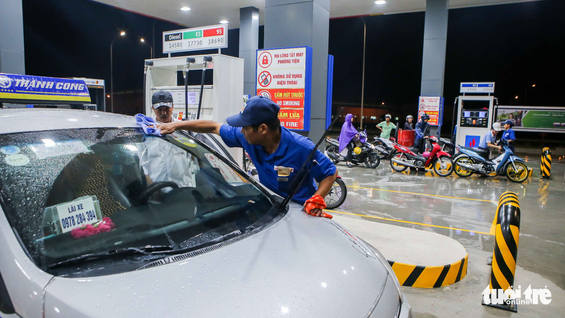 An Idemitsu Q8 employee provides a free windshield cleaning service to a car. Photo: Tuoi Tre