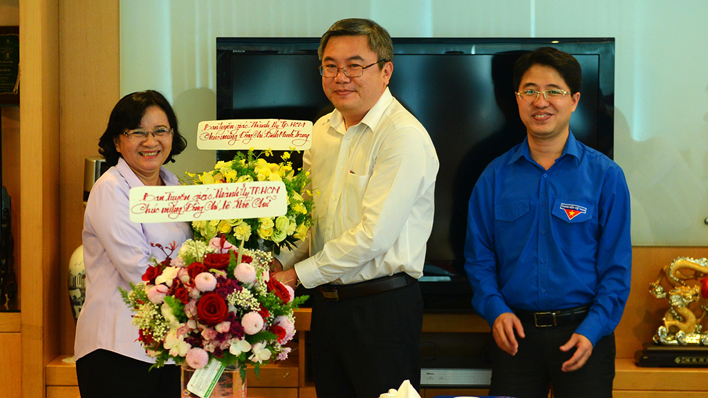 Dinh Minh Trung (C), Deputy Editor-in-Chief of Tuoi Tre, receives congratulatory flowers from Than Thi Thu (L), head of propaganda at the Party Committee of Ho Chi Minh City, October 23, 2017. Photo: Tuoi Tre