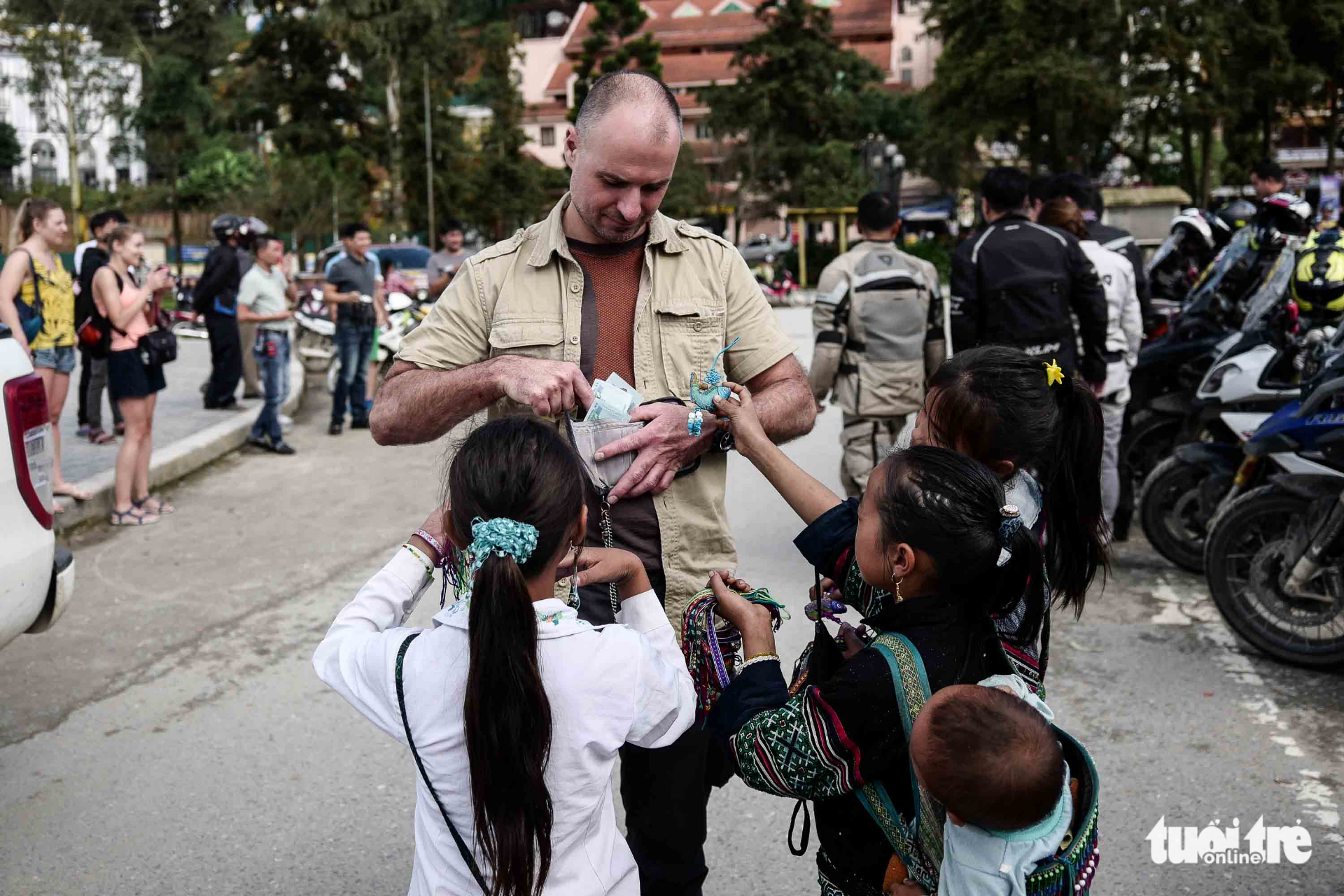 A foreign tourist takes out money from his wallet to buy souvenirs from local children.