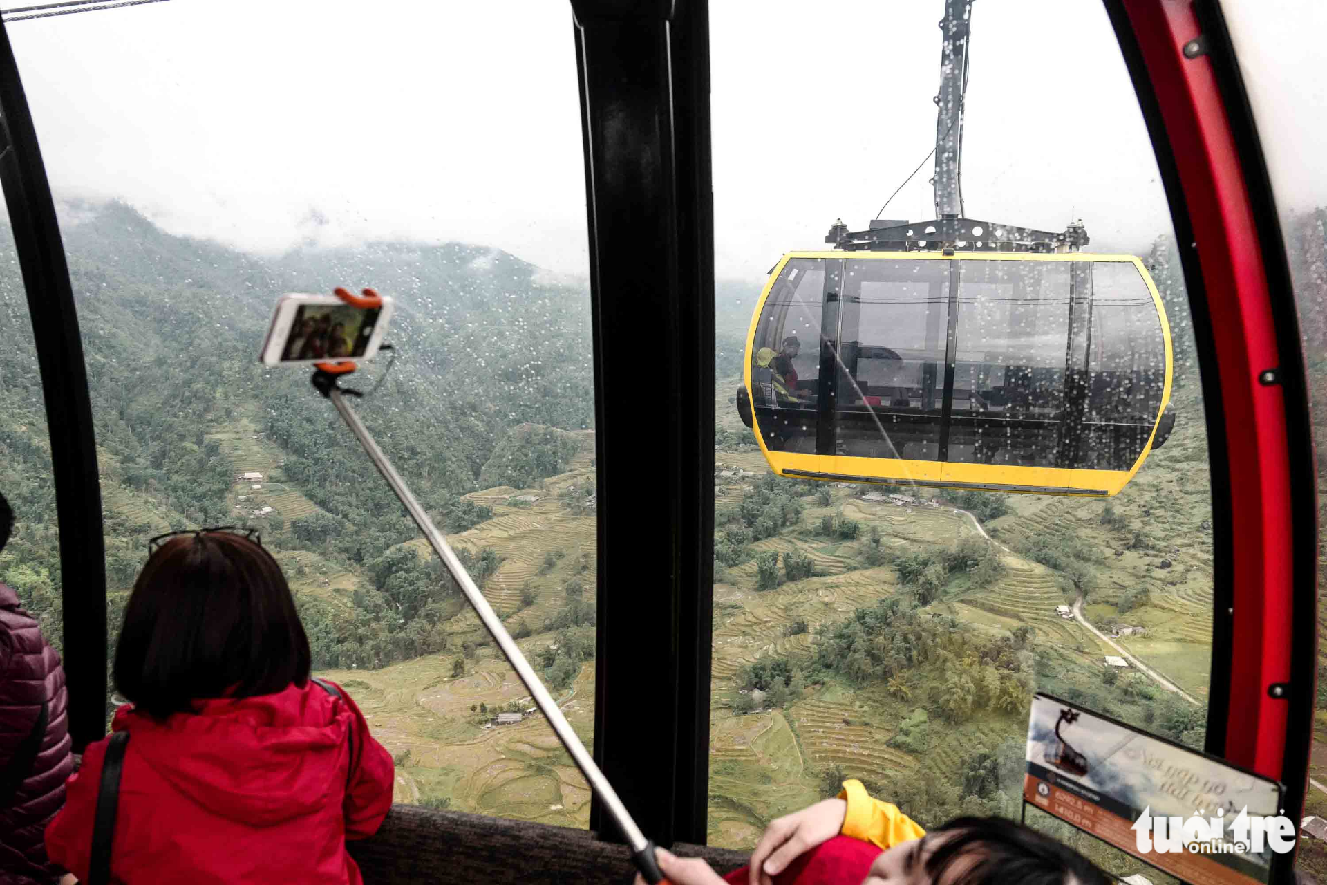 A group of visitors take selfies during their cable car journey.