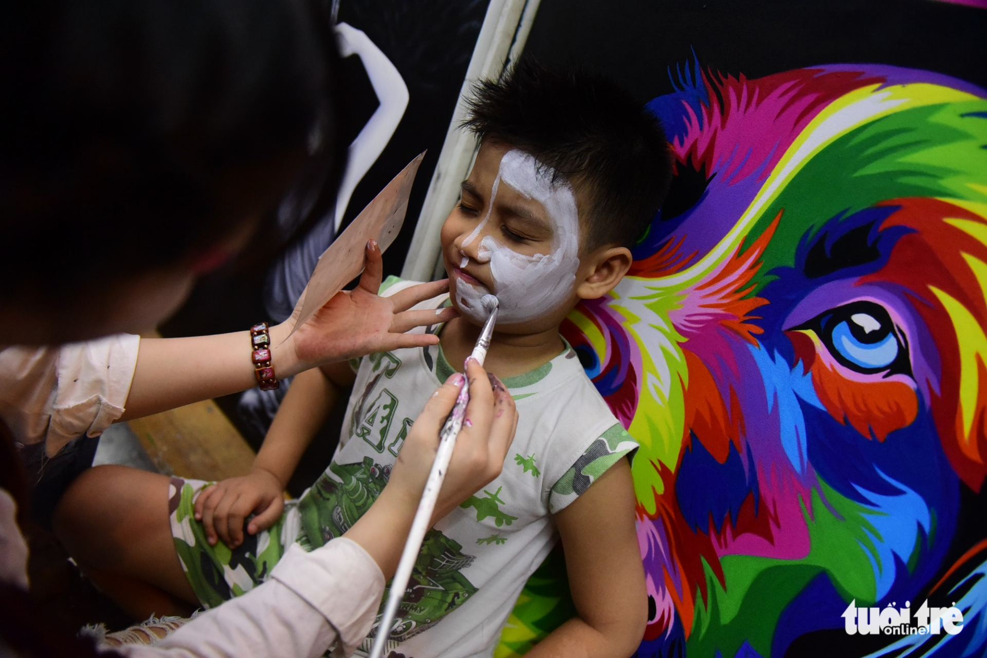 A young boy gets his face painted.