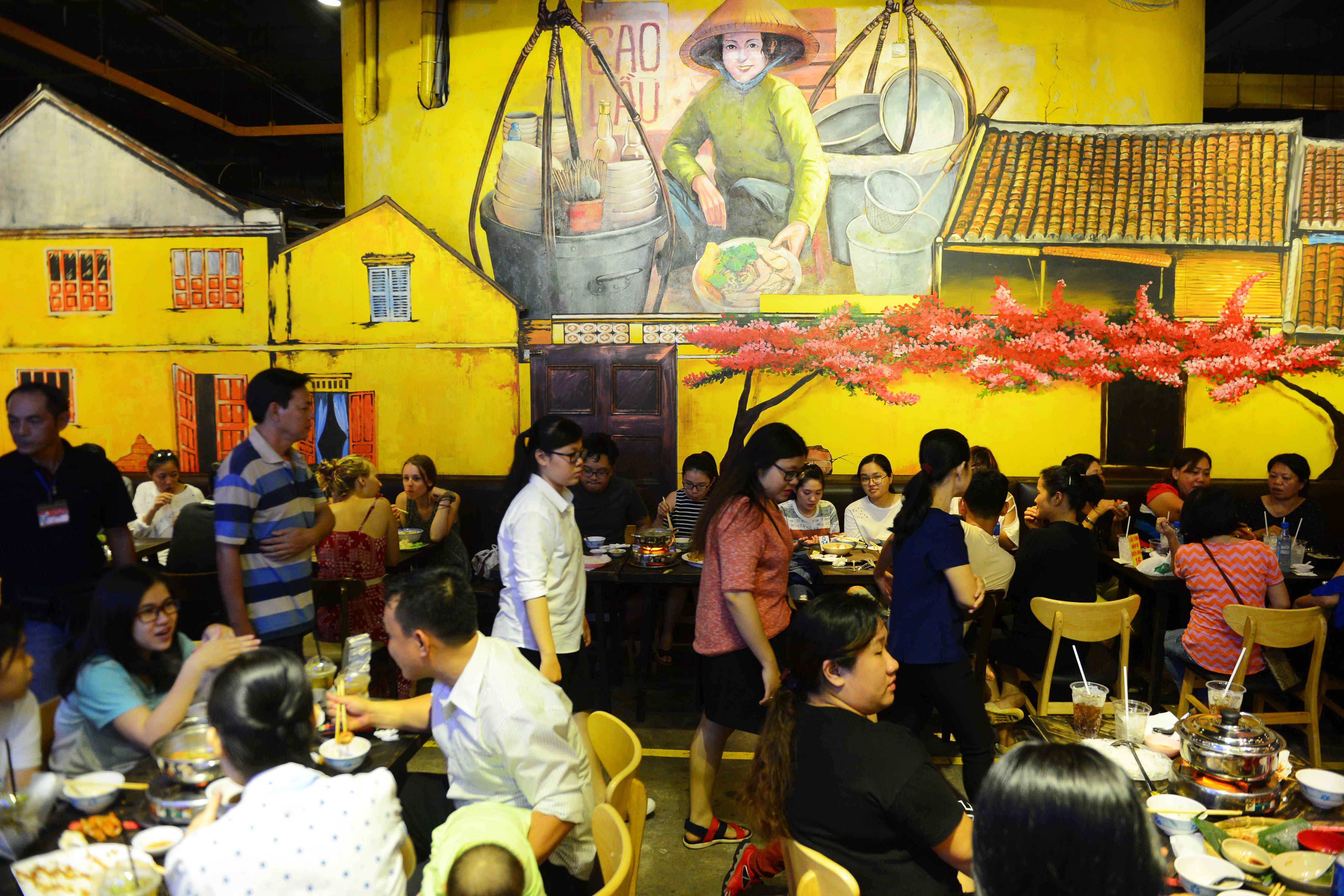 The venue is decorated with paintings highlighting traditional Vietnamese culture and cuisine.