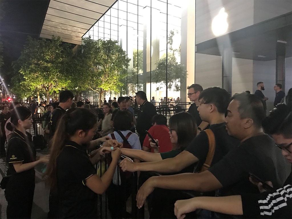 Apple store employees attach wrist tags to queuers. Photo: Tuoi Tre