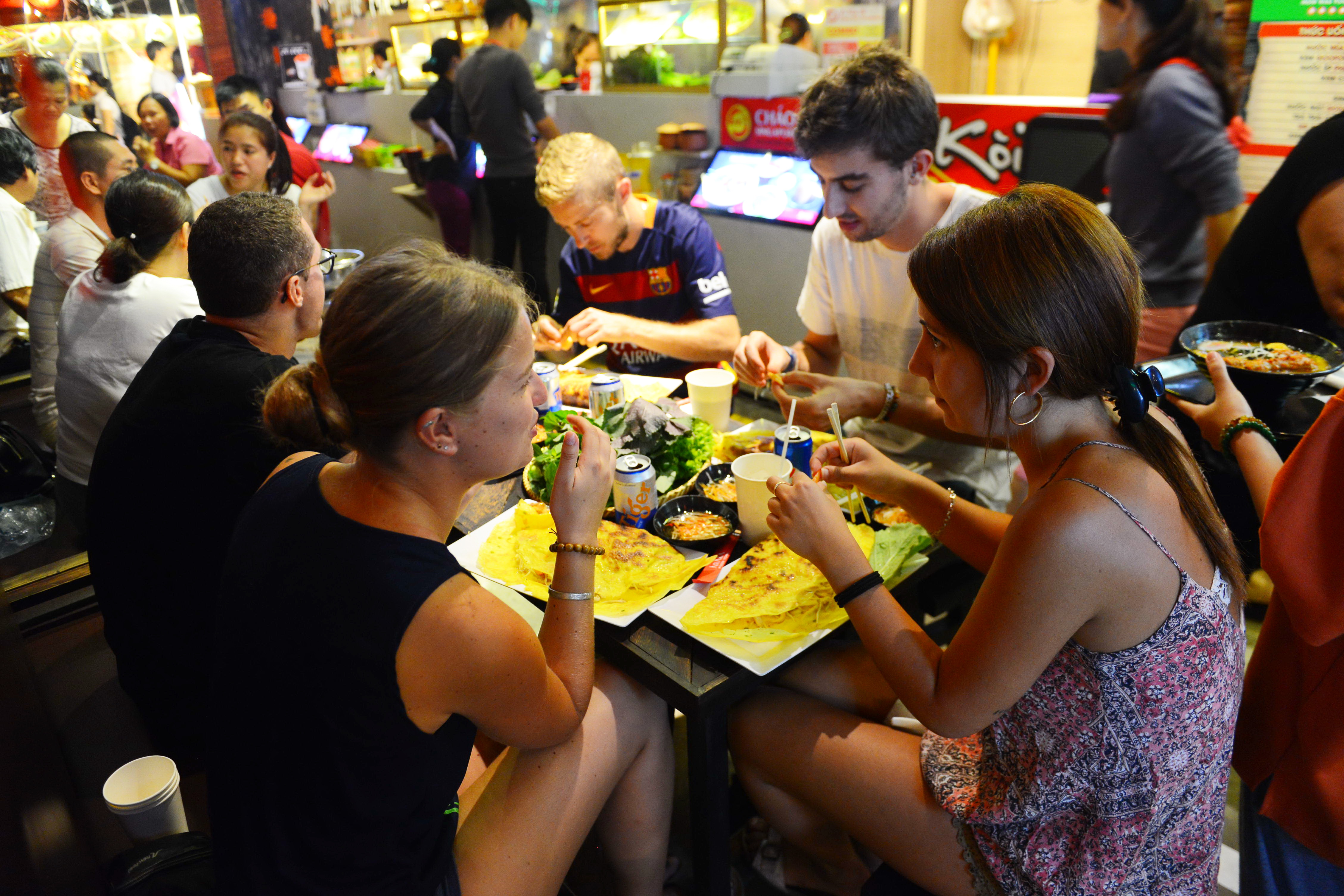 A group of visitors from France and Spain enjoy ‘banh xeo,’ a traditional Vietnamese pancake, at the Asiana Food Town.