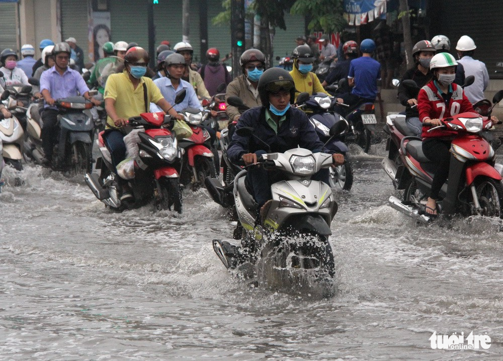 People face difficulties traveling on a flooded street.