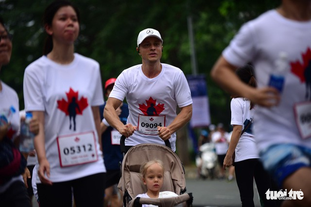 A foreign man pushes his daughter on a baby carriage during the charity run.