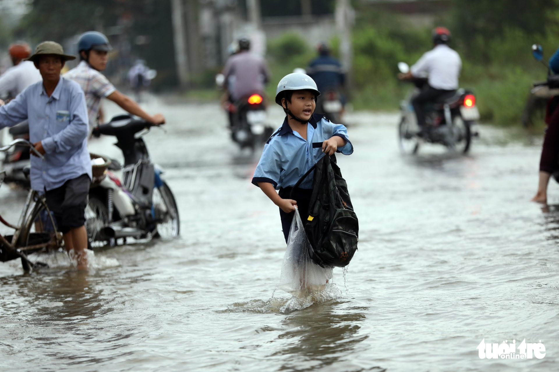 A young student holds a wet backpack after dropping in the water.