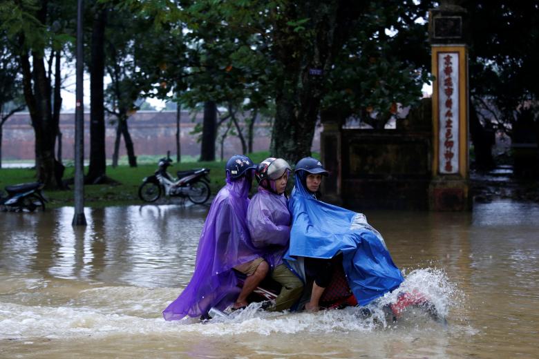 People ride a motorcycle along a flooded road in Hue. Photo: Reuters