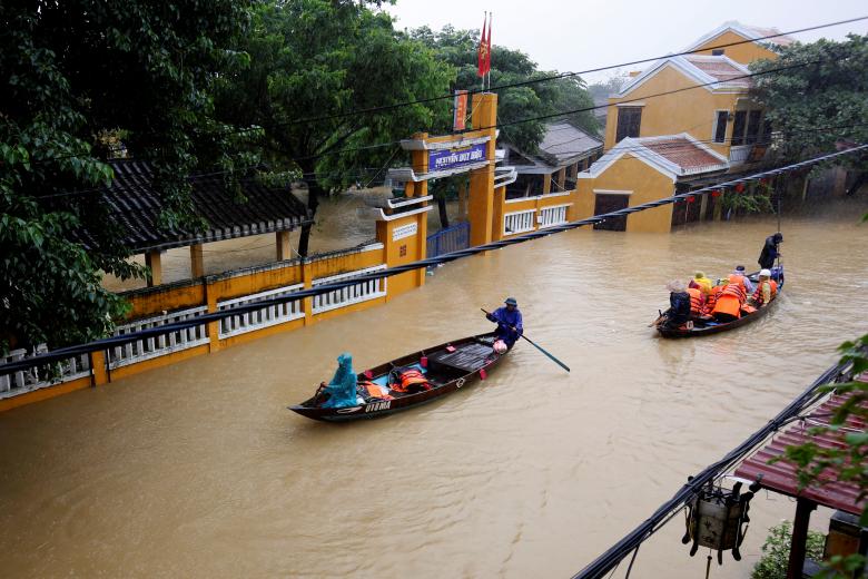 People ride a boat along submerged houses in Hoi An. Photo: Reuters