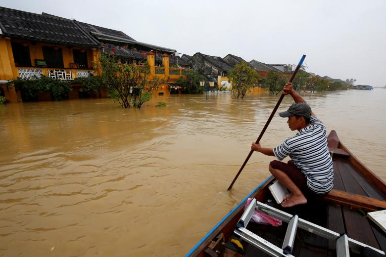 A man rides a boat along the overflowing Thu Bon river in Hoi An. Photo: Reuters