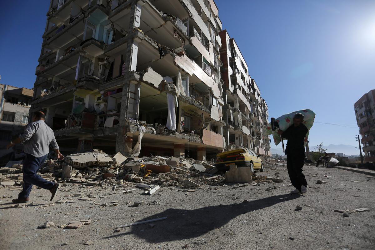 People walk past a damaged building following an earthquake in Sarpol-e Zahab county in Kermanshah, Iran November 13, 2017. Photo: Reuters