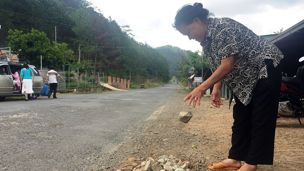 Le Thi Ky, a resident living at the foot of Mimosa Pass, collects rocks from the road.