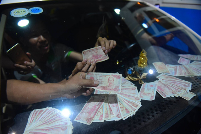 Drivers prepare small denomination banknotes to pay their toll.