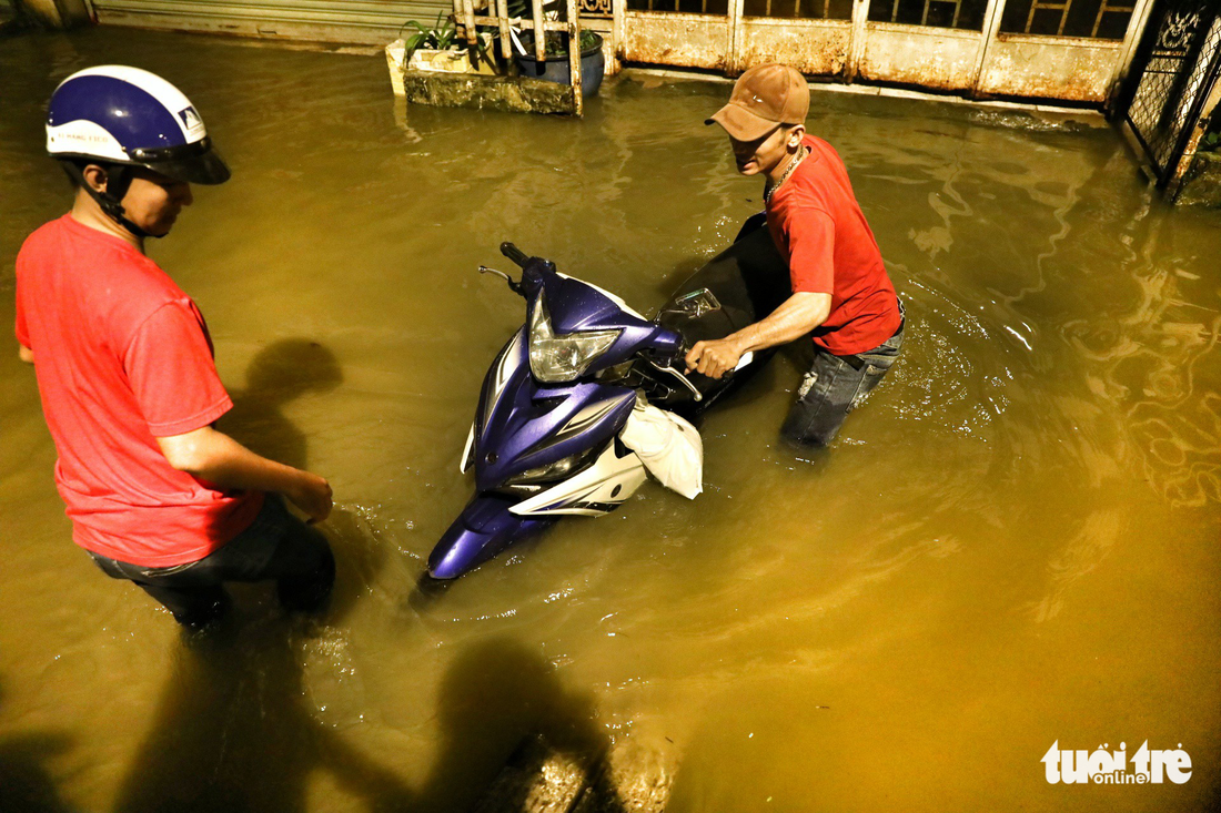 A man pushes his motorbike along an inundated road in Ho Chi Minh City.