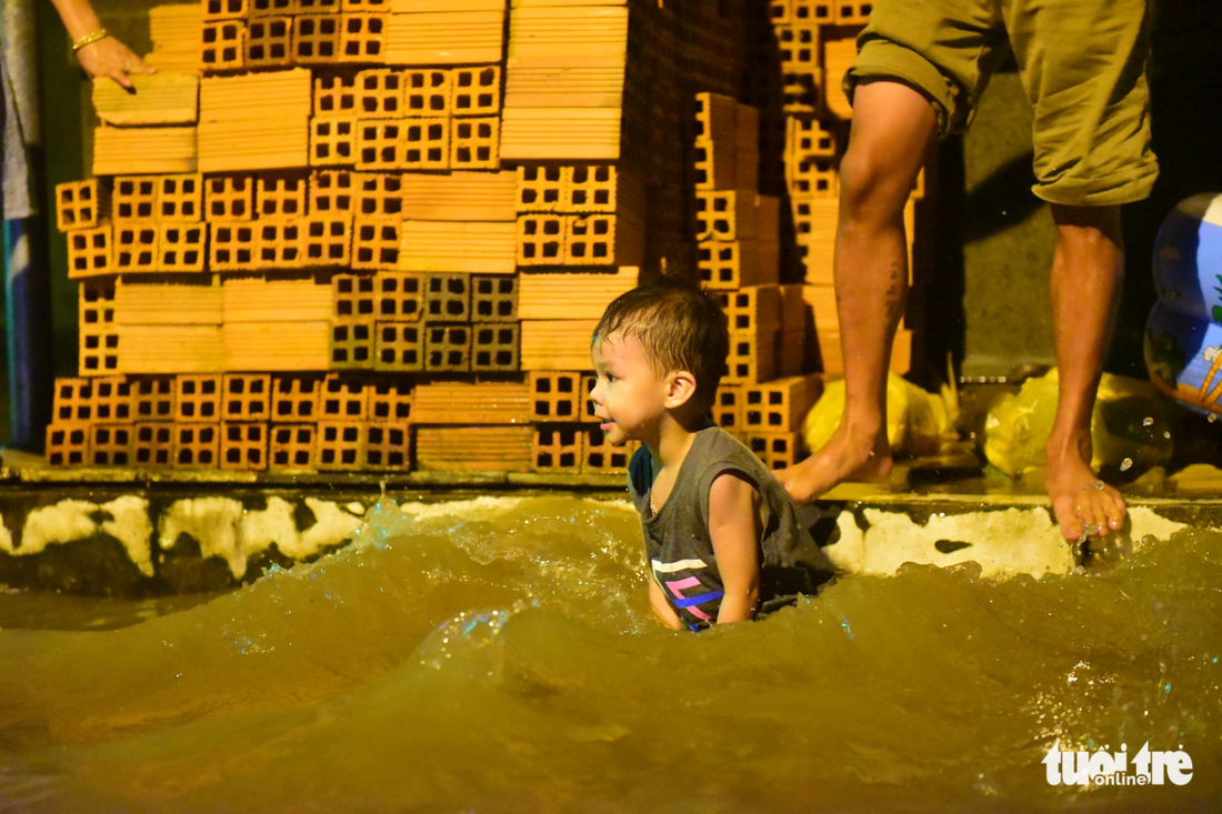 A young boy enjoys himself on a flooded street.