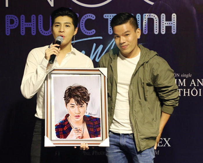 Tran Thien Sy (R) presents his portrait of Vietnamese singer Noo Phuoc Thinh to the singer. Courtesy of Sy