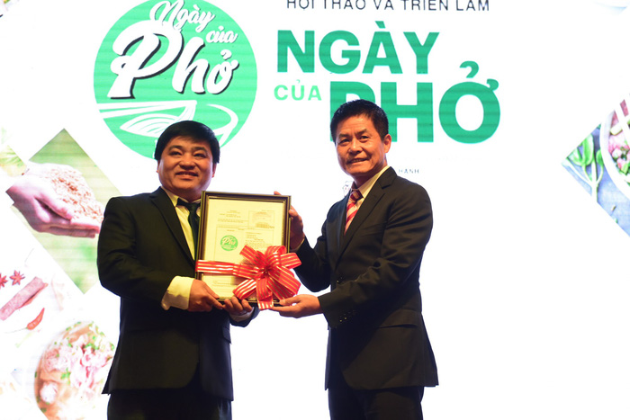 Nguyen Quoc Ky (R), chairman of Vietnam Cuisine Culture Association, presents Le The Chu, Editor-in-Chief of Tuoi Tre (Youth) newspaper, with a certificate of intellectual property over the logo of Pho Day at the event's first edition in Ho Chi Minh City, December 12, 2017. Photo: Tuoi Tre