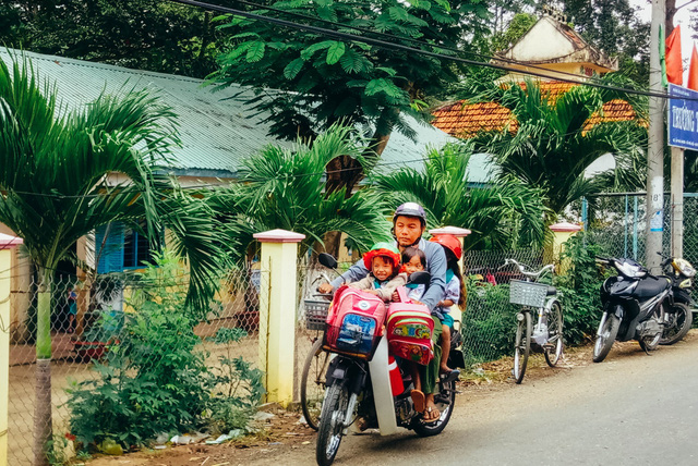 Nguyen Van Hoi carries three children on his old motorbike. Photo: Pham Minh Hien