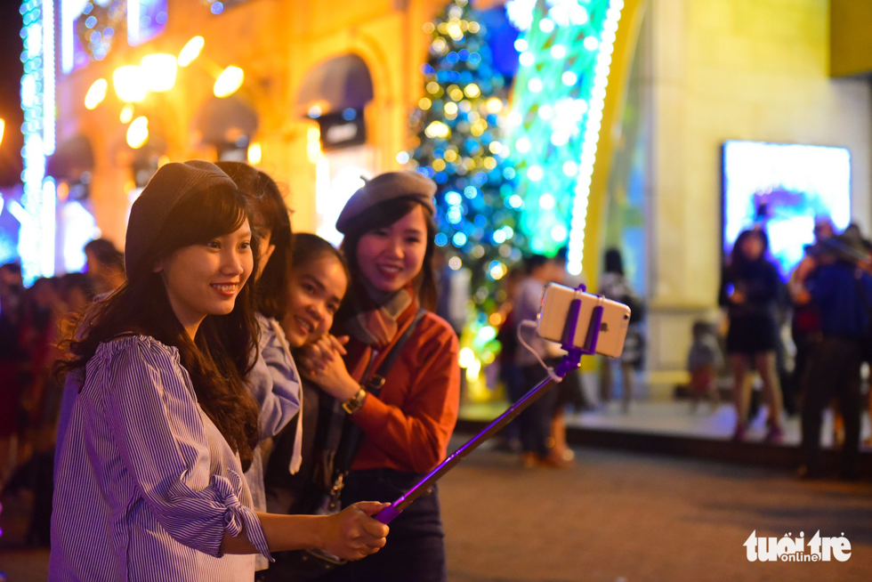 A group of young ladies pose in front of a vividly decorated shopping mall. Photo: Tuoi Tre