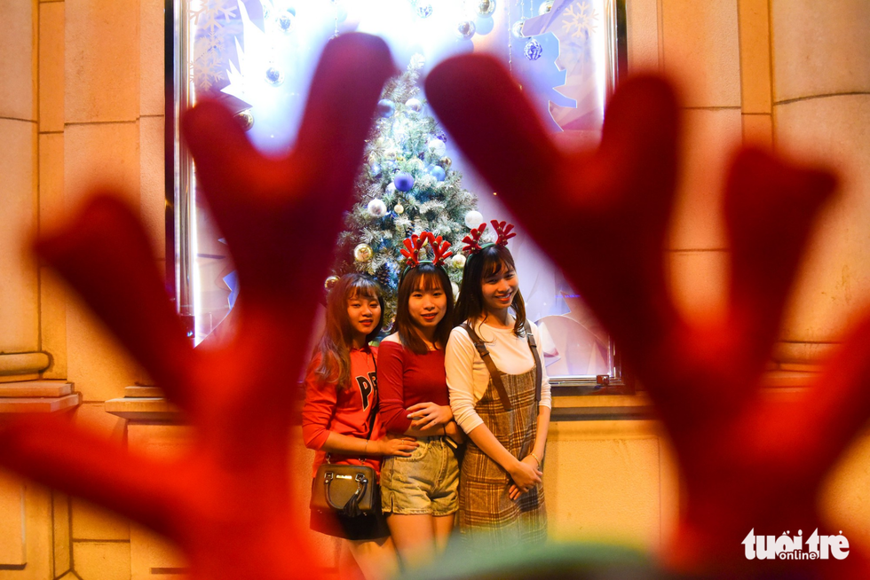 A group of young ladies pose in front of a vividly decorated shopping mall. Photo: Tuoi Tre