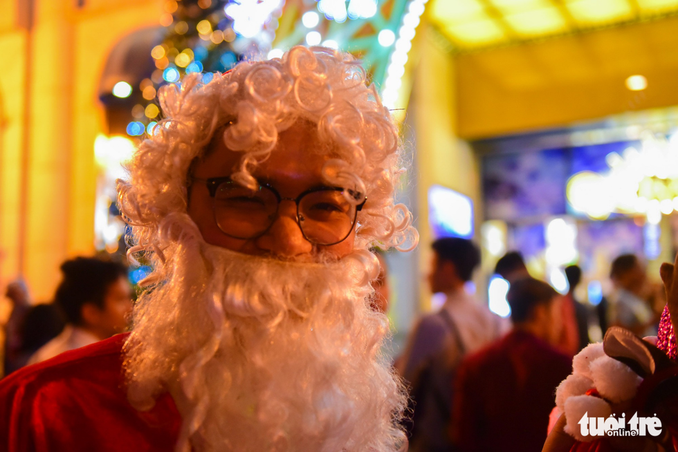 A young man wears a Santa Claus costume to sell Christmas stuff like reindeer headbands and Noel hats. Photo: Tuoi Tre
