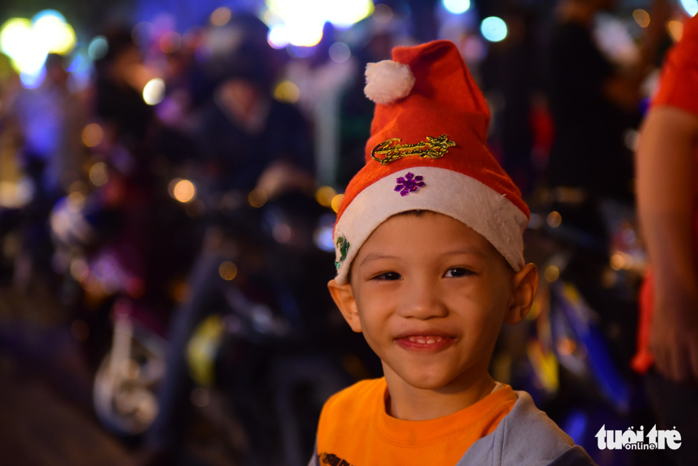 A kid smiles while hanging out with his parents for Christmas celebration. Photo: Tuoi Tre