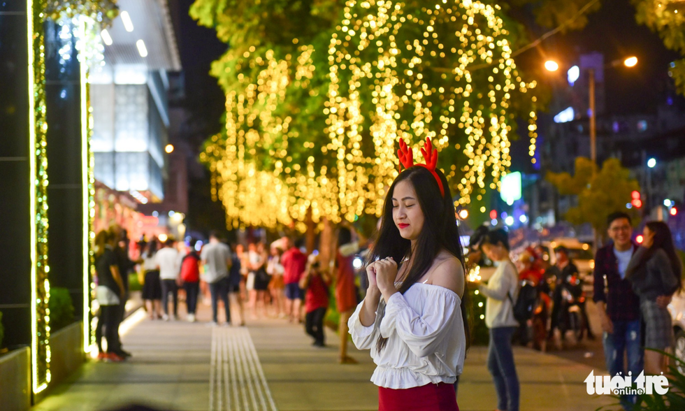 A young lady wears a reindeer headband outside a shopping mall in District 1, Ho Chi Minh City. Photo: Tuoi Tre