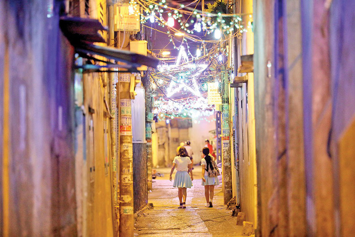A small alley on Pham The Hien Street is lit up with Christmas lights.