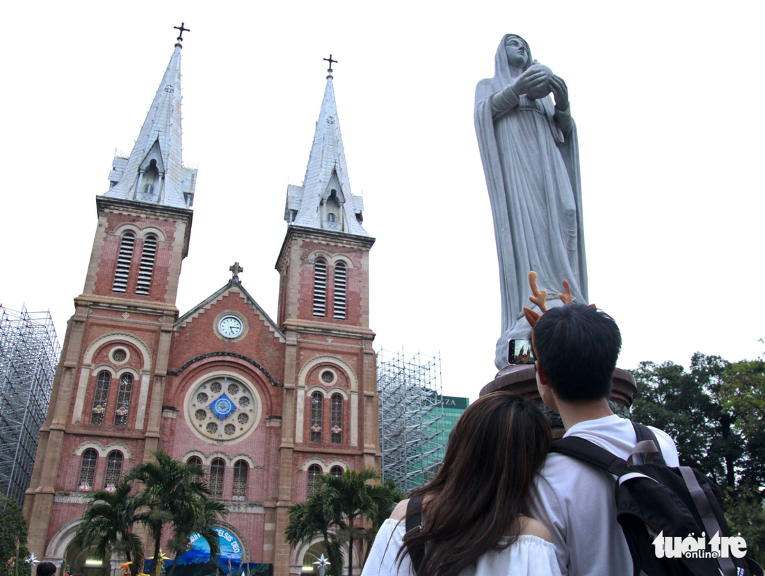 A young couple take a photo of the Notre-Dame Cathedral Basilica of Saigon on December 24, 2017.