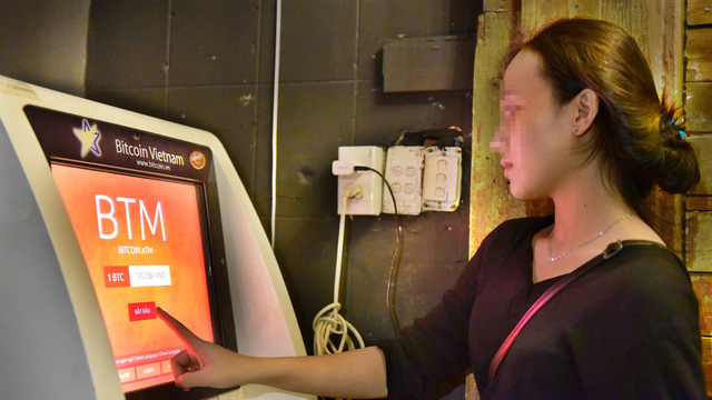 A woman accesses her account on a bitcoin ATM in Ho Chi Minh City. Photo: Tuoi Tre