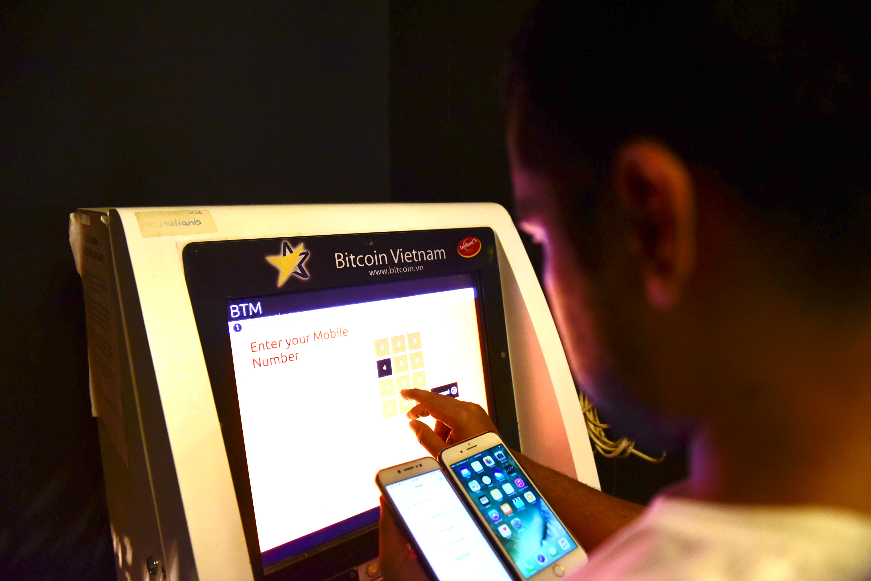 A man taps on the screen of a bitcoin ATM in Ho Chi Minh City. Photo: Tuoi Tre