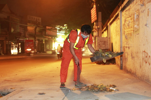 A sanitation worker is busy clearing the streets of trash as usual. Photo: Tuoi Tre