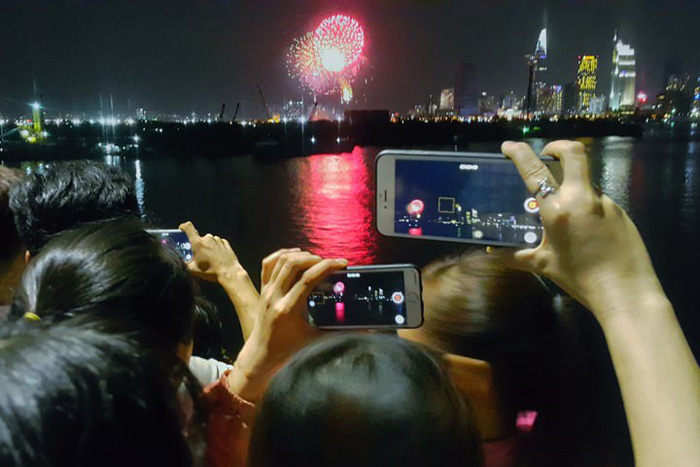 People film a fireworks display to ring in New Year on January 1, 2018. Photo: Tuoi Tre